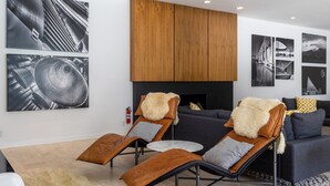 A modern living room with a sofa, two lounge chairs, a fireplace, and three large black-and-white photographs on the wall. - Apollo 1000 - Space Age Luxury Palm Springs Retreat (Palm Springs)