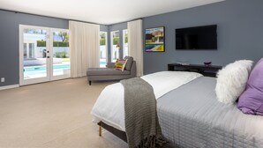 A bedroom with a bed, a TV, a painting, and a view of a pool. - Apollo 1000 - Space Age Luxury Palm Springs Retreat (Palm Springs)