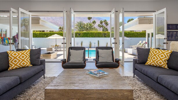 A modern living room with two sofas, a coffee table, and a pool view. - Apollo 1000 - Space Age Luxury Palm Springs Retreat (Palm Springs)