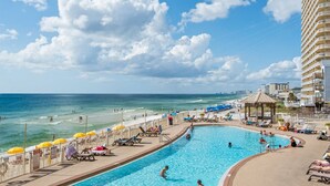 A swimming pool with a view of the ocean and a beach area with umbrellas and lounge chairs. - 207-2nd Floor-Two King Beds-AMAZING BEACH VIEWS!!!!!-Outdoor Pool-Hot Tub (Panama City Beach)