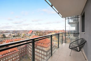 En balkong med fri utsikt över stadsbilden, en glasvägg och en svart stol.