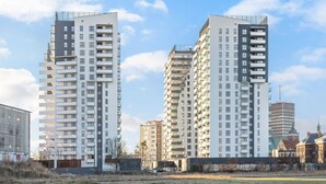 Deux immeubles résidentiels de grande hauteur dotés de balcons, un ciel dégagé et un chantier de construction au premier plan.