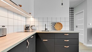 Une cuisine moderne avec un plan de travail en bois, des armoires noires et un pare-feu à rayures.