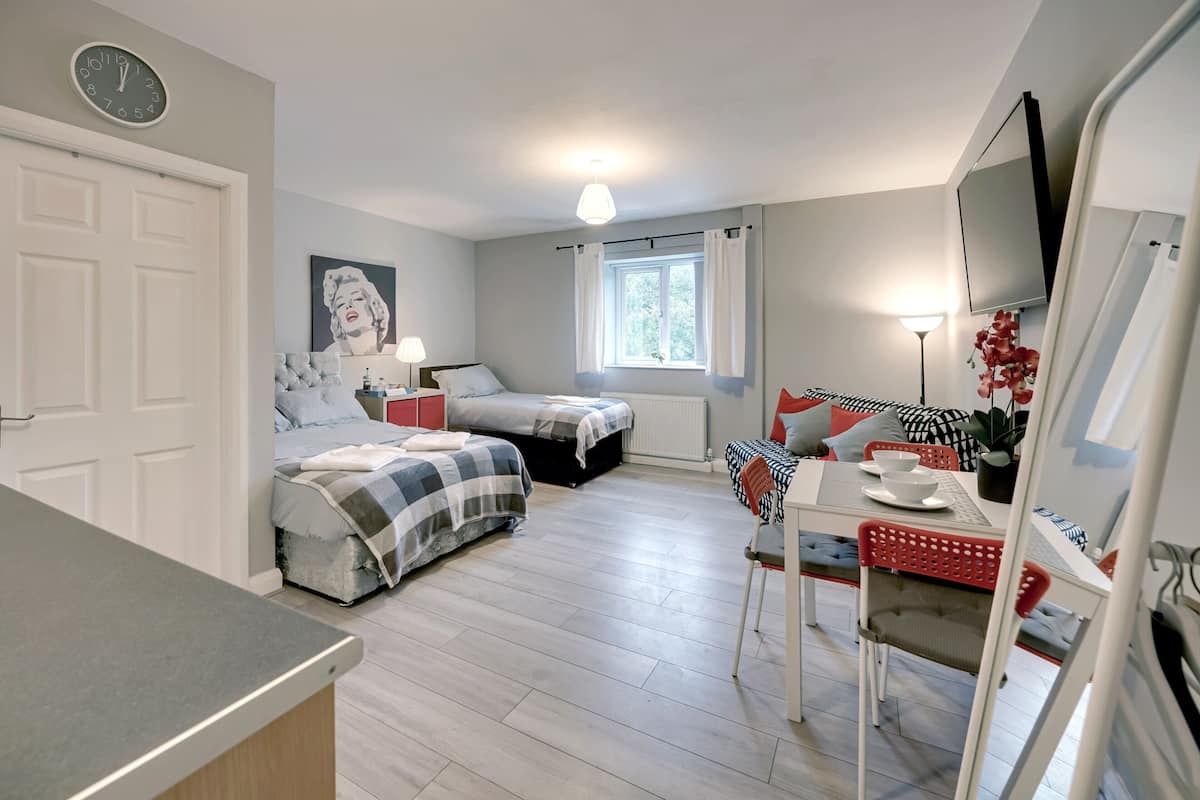 A compact bedroom with two beds, a dining area, and a TV.