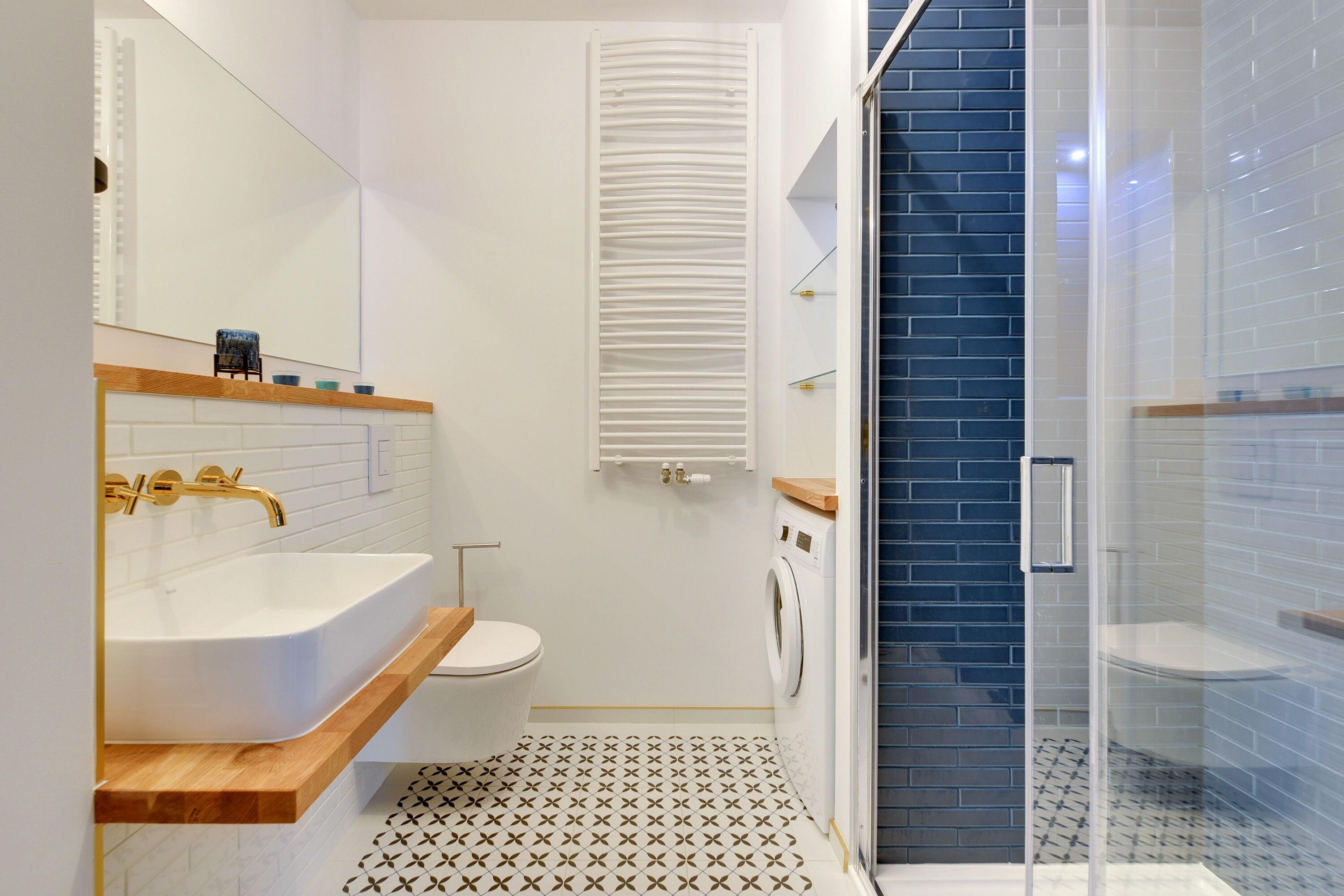 A modern bathroom with a freestanding bathtub, a toilet, a washing machine, and a glass shower enclosure.