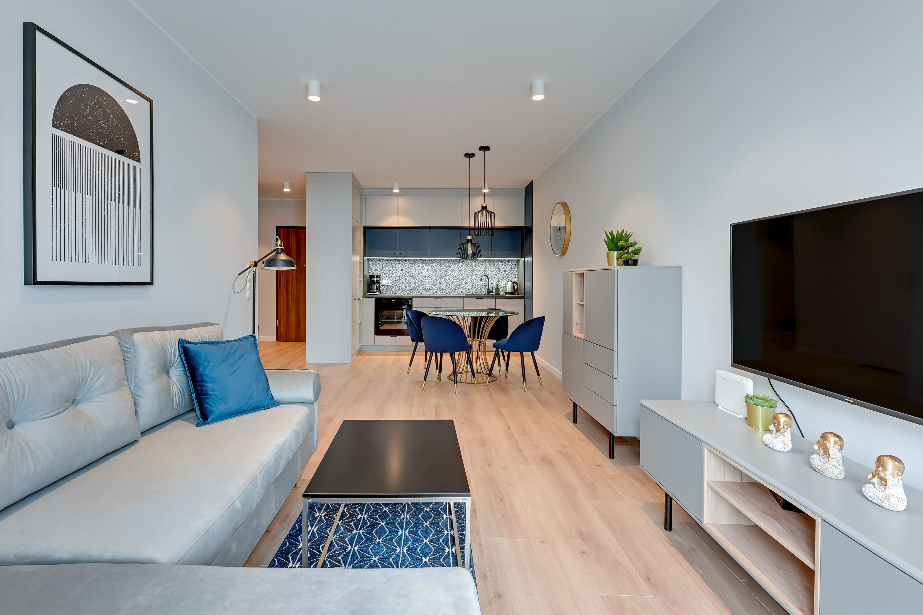 A modern living room with a grey sofa, a coffee table, and a TV stand with decorative items.
