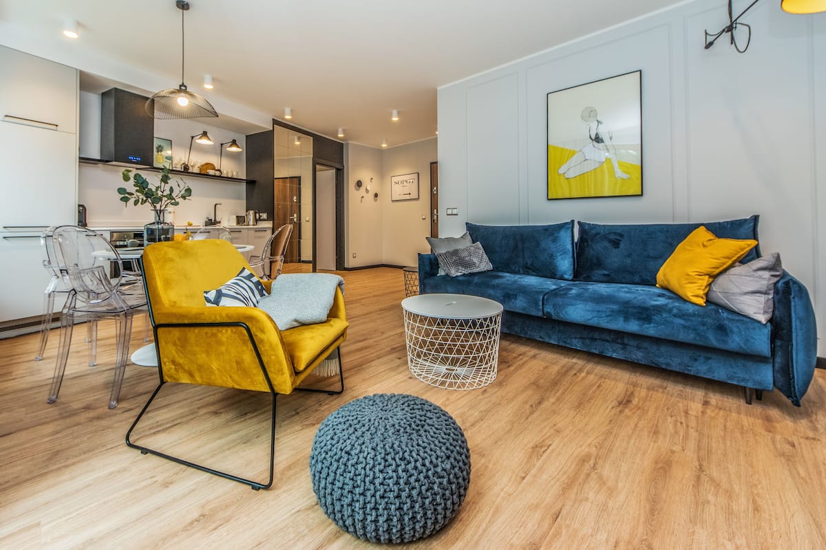 Een moderne woonkamer met een gele fauteuil, een blauwe bank en een rond hockertje.