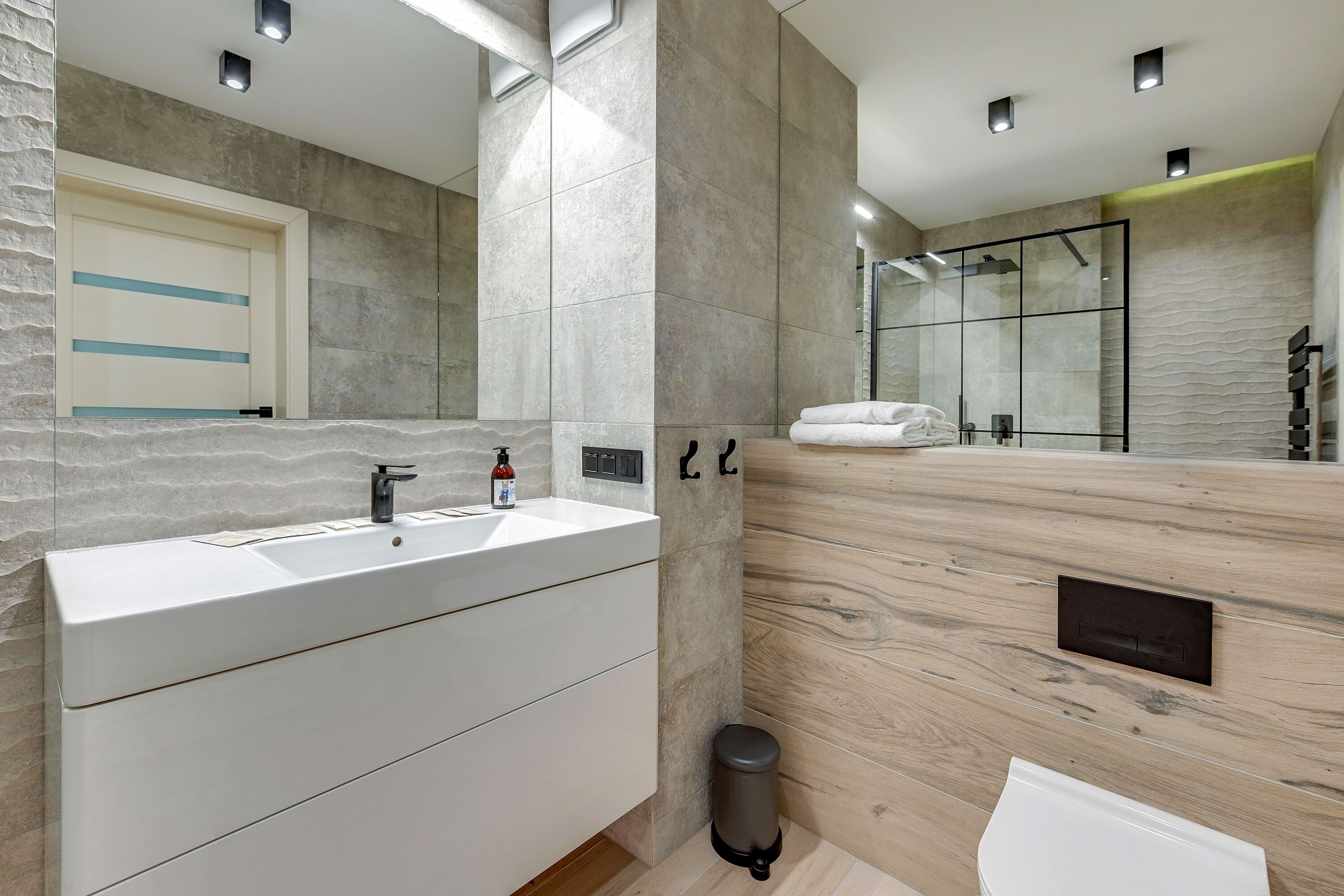 Un baño moderno con un espejo grande, un lavabo y una zona de ducha.