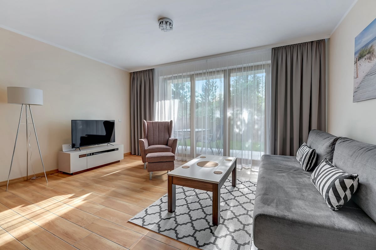 Een moderne woonkamer met een bank, een televisie op een standaard, een stoel en een salontafel.