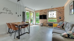 A modern living room with a dining area, a fireplace, and a large window offering a view of the outdoors.