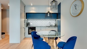 A modern kitchen with blue cabinets, a patterned backsplash, and a round table with blue chairs.