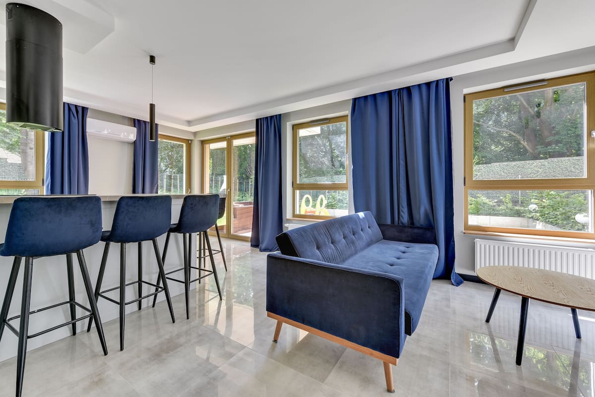 Een moderne woonkamer met een bank, barstoelen en een ronde tafel.