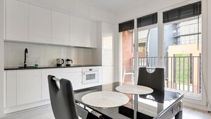 Une cuisine moderne avec des meubles blancs, un plan de travail noir et une table à manger avec deux chaises.