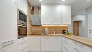 Une cuisine moderne avec des meubles blancs, un plan de travail en bois et des appareils électroménagers en acier inoxydable.