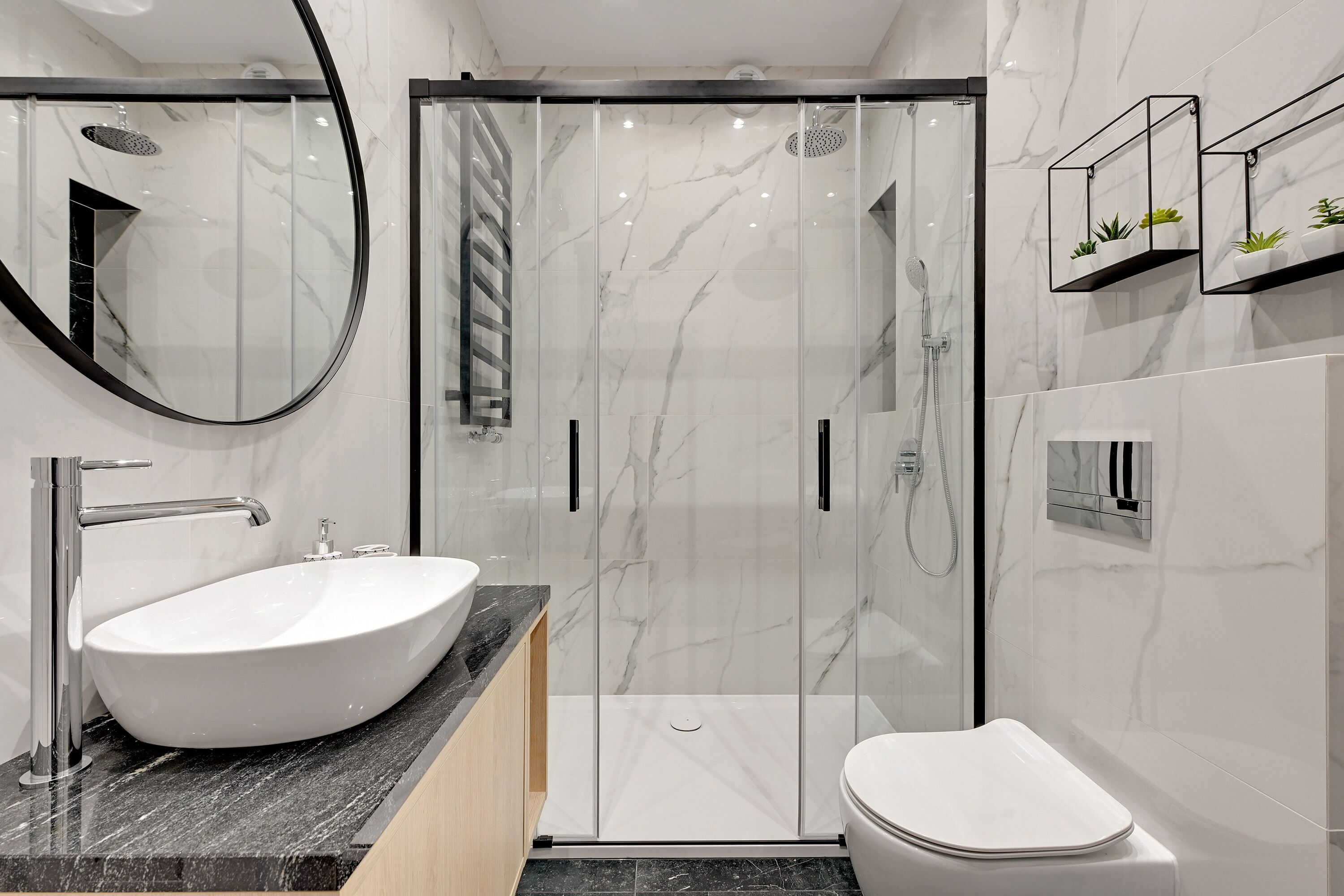 Een moderne badkamer met een witte wastafel, toilet en een douche met glazen wanden.