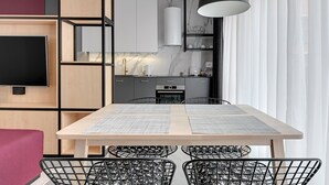 Une cuisine moderne dotée d’un îlot central, d’un coin repas avec une table et des chaises, et d’un téléviseur fixé au mur.