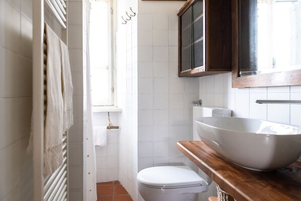 Un bagno compatto con il water bianco, un mobile bagno in legno con un ampio lavabo bianco e una finestra sopra il water.