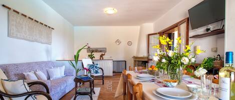 A dining area with a table set for four, a sofa, and a kitchen in the background.