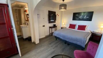 Een hotelkamer met een bed, een bureau, een stoel, een televisie en een badkamer.