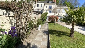 A pathway leading to a building with a stone facade, surrounded by greenery and a clear blue sky. - Les Rives du Cher (Montrichard Val de Cher)