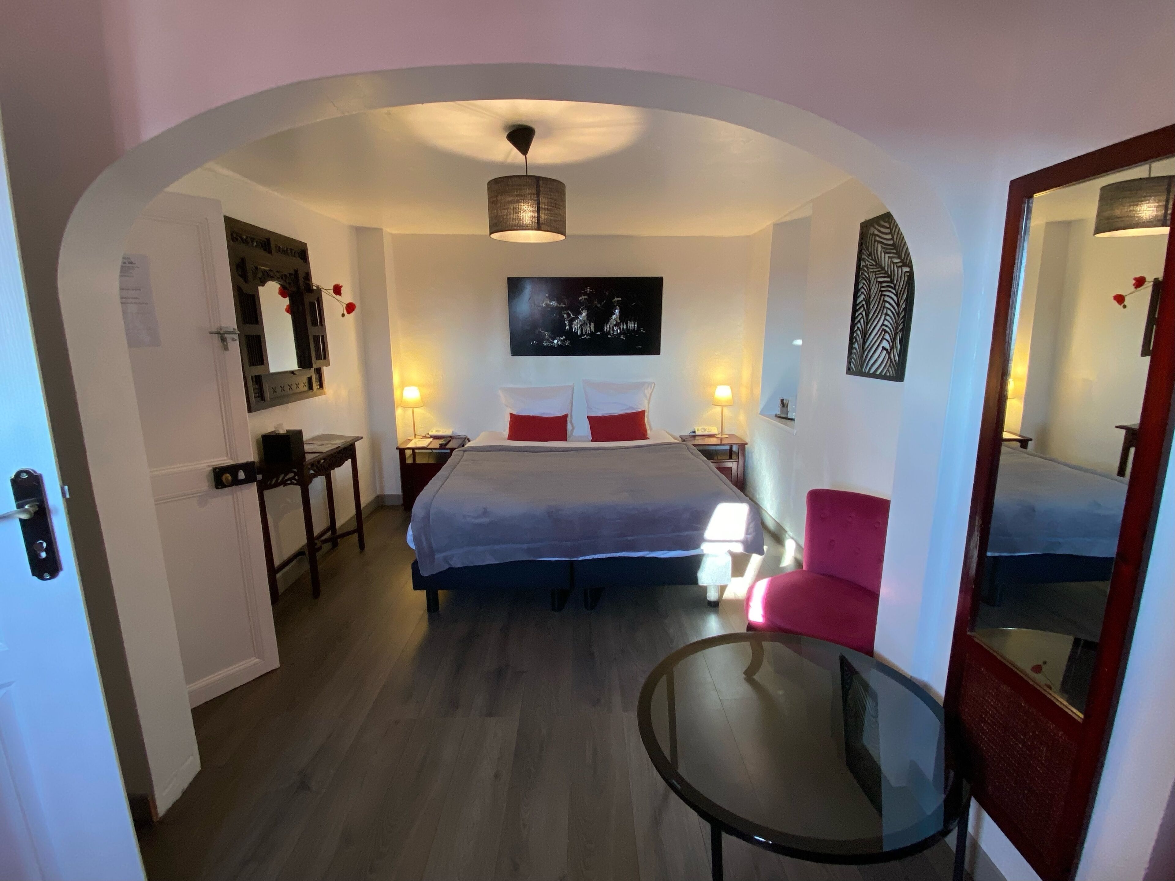 Habitació d'hotel amb llit, escriptori, cadira, taula petita i mirall.