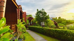 A pathway leading to a building with a traditional architectural style, surrounded by well-maintained greenery and a clear sky. - Druwa Bali (Kutuh)