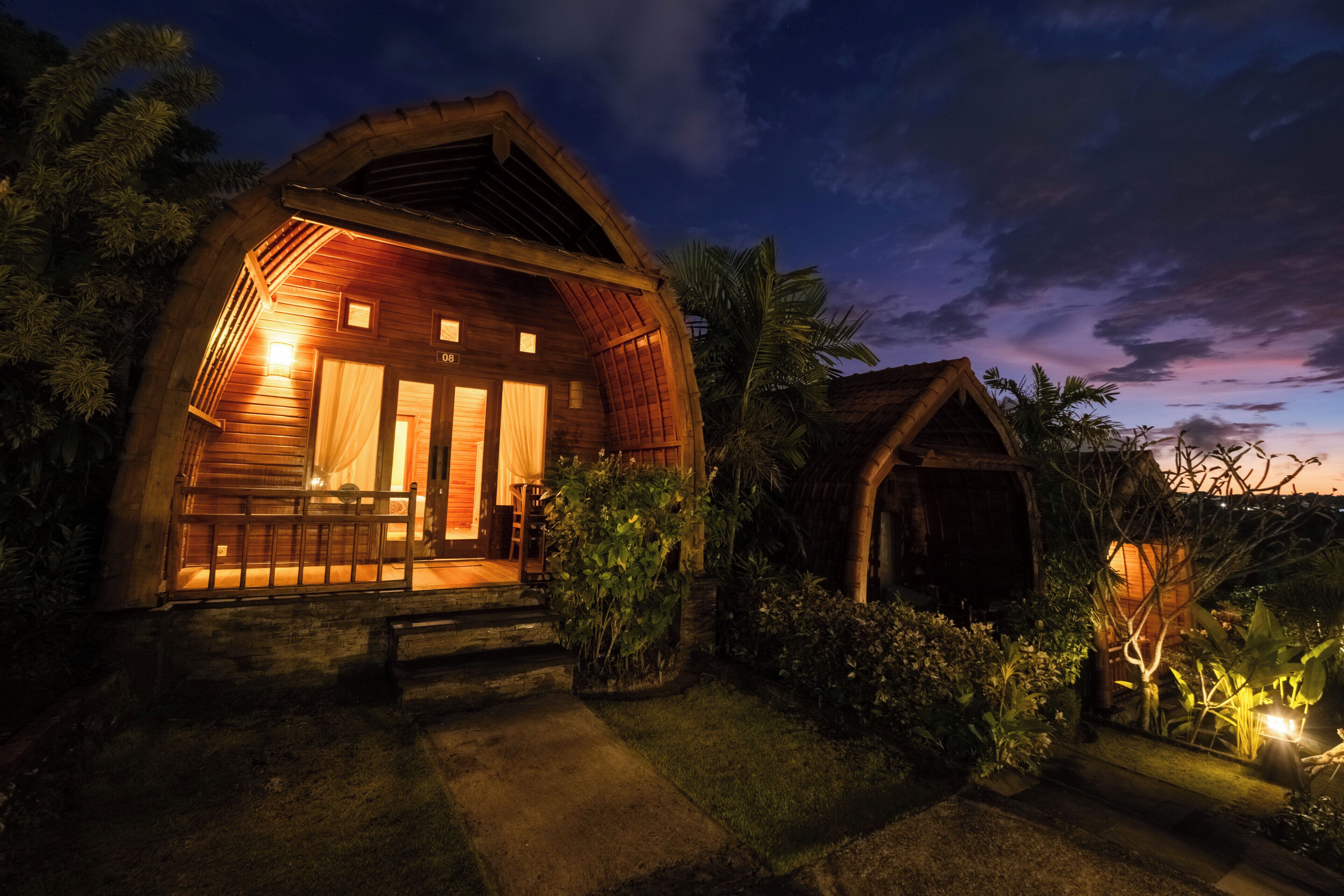 A wooden cabin with a porch, surrounded by vegetation.