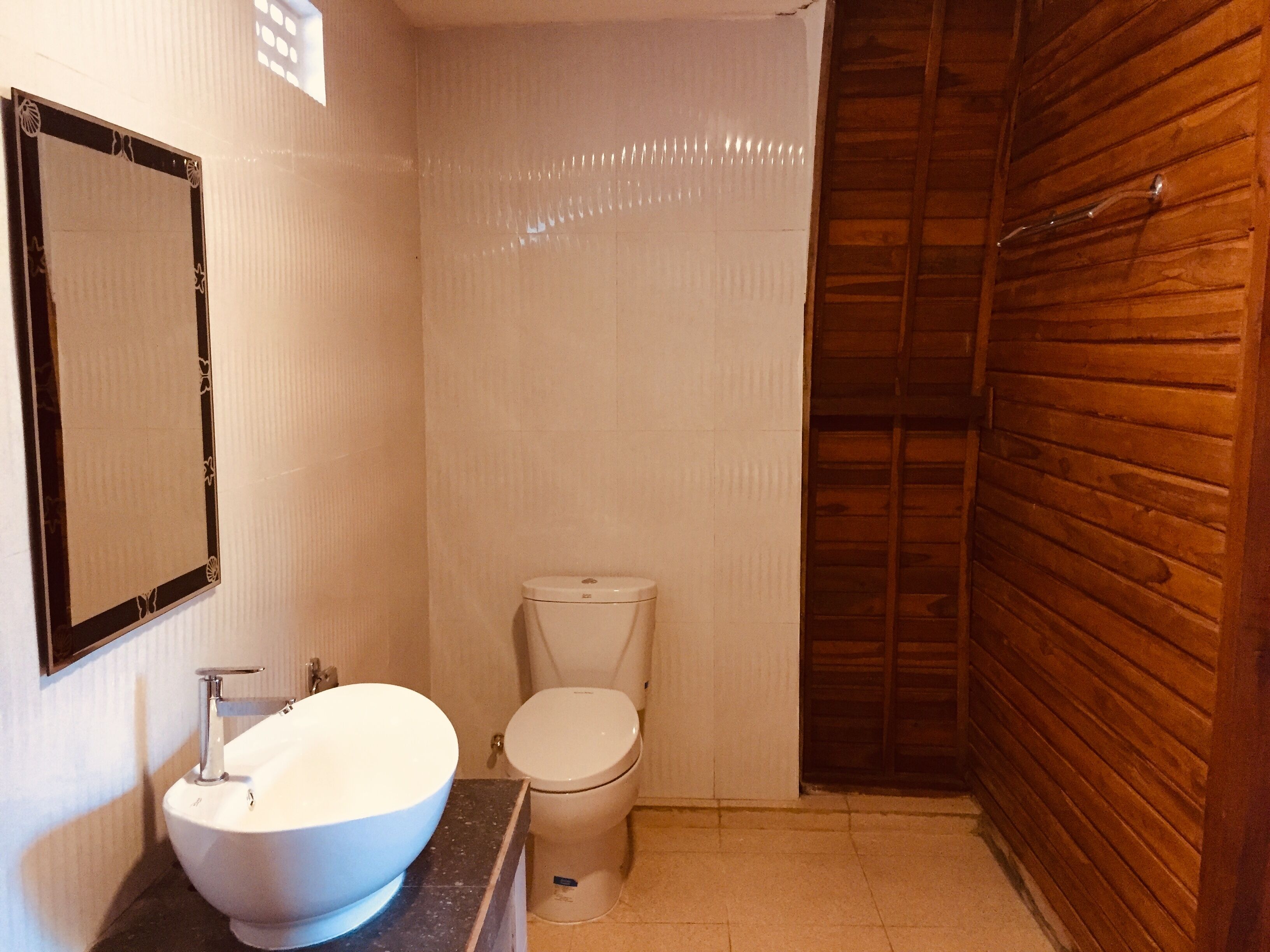 A bathroom with a white sink, toilet, and wooden walls.