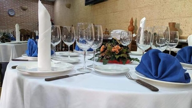 Een gedekte tafel, met witte tafelkleden, blauwe servetten en transparante glazen.
