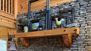 A stone fireplace with a wooden mantel shelf, a mirror, and a lamp on a side table. - LARGE elegant DESIGNER mountain cabin home on RIVER COOSAWATTEE perfect4families (ellijay)