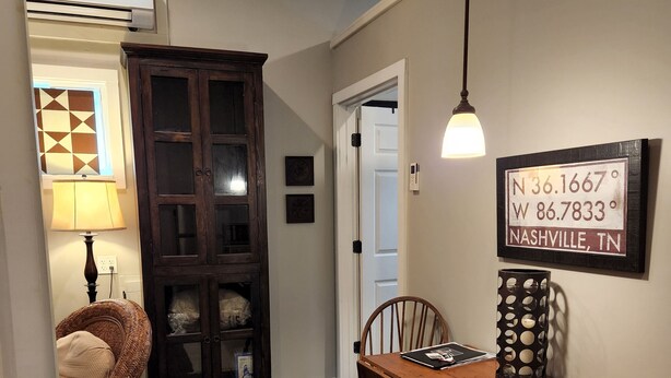 Un coin repas avec une table en bois, des chaises, un tapis et un panneau fixé au mur indiquant que l’on se trouve à Nashville, dans le Tennessee.