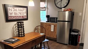 Une cuisine avec une table en bois, une horloge et un réfrigérateur.