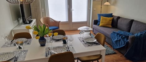 A dining area with a table set for four, a sofa, and a lamp.