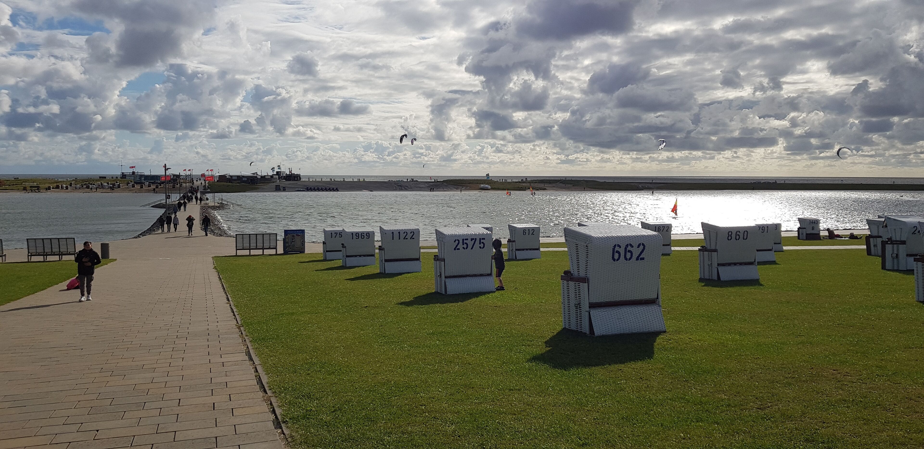 Un parc au bord de l’eau, avec des tombes numérotées, une promenade dallée et une vue sur la mer.