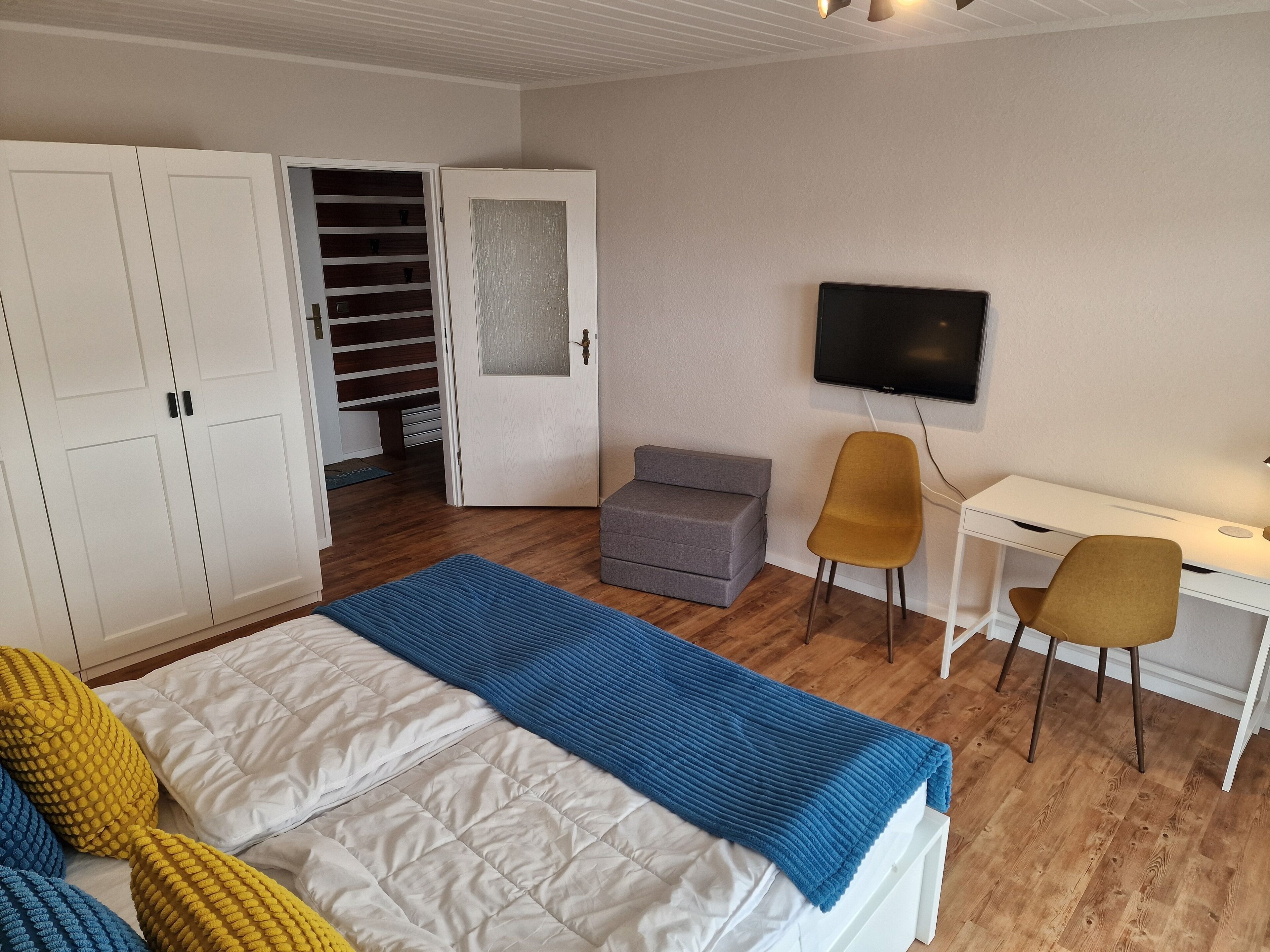 Une chambre à coucher comprenant un lit, un bureau, une chaise, une télévision et une armoire.