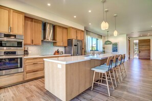A modern kitchen with wooden cabinets, stainless steel appliances, and a central island with bar stools.