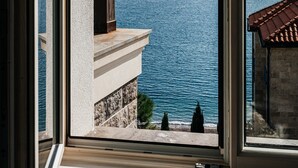 A view from a window overlooking a coastal area with a clear sky and calm sea. - Lustica Bay Marina (Radovici)