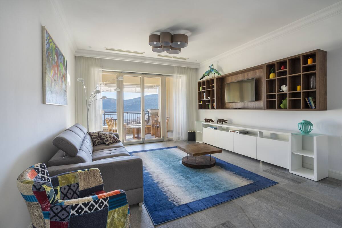 A modern living room with a sofa, a coffee table, a large TV, and a bookshelf.