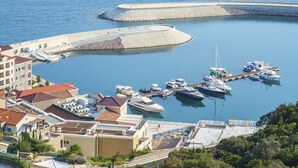 A marina with boats docked, buildings with red roofs, and a clear blue sky. - Lustica Bay Marina (Radovici)