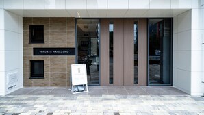 Une entrée moderne d’un bâtiment, avec une enseigne indiquant : « KAUNIS HANAZONO GRANDOUCE ».