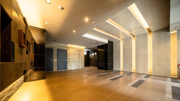 Un hall d’entrée spacieux au design moderne, avec un mélange de revêtements de sol en bois et en carrelage, un éclairage encastré et un espace central dédié à l’ascenseur.