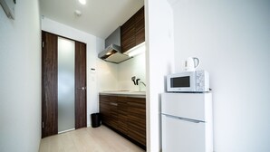 Une cuisine moderne équipée d’un four à micro-ondes, de meubles en bois et d’un réfrigérateur blanc.