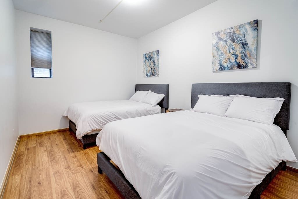 Ein Schlafzimmer mit zwei Betten, Holzböden und abstrakter Kunst an den Wänden.