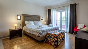 A hotel room with a bed, bedside table, lamp, and a view of the outdoors through a sliding glass door.