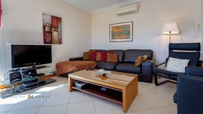 A modern living room with a flat-screen TV, a leather sofa, a coffee table, and a framed picture on the wall.