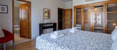 A hotel room with a bed, a desk, a chair, and a wardrobe.
