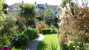A garden pathway leading to a house with a brick entrance.