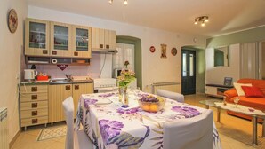 Une cuisine moderne avec des meubles en bois et un coin repas agrémenté d’une nappe à motifs floraux.