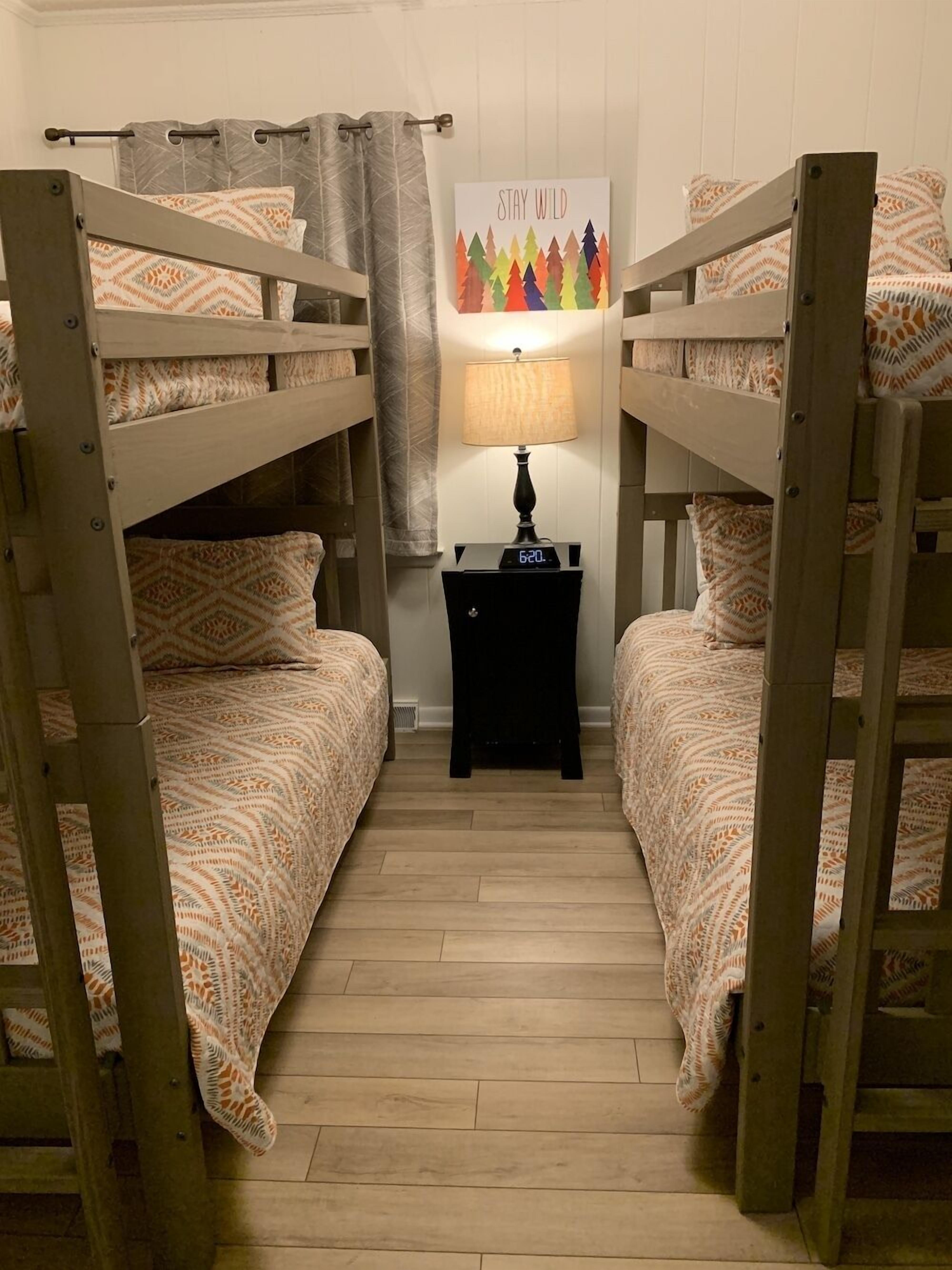A room with two bunk beds, a nightstand with a lamp, and a 'Stay Wild' poster on the wall.