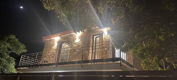 A stone building with a balcony, illuminated by exterior lights.